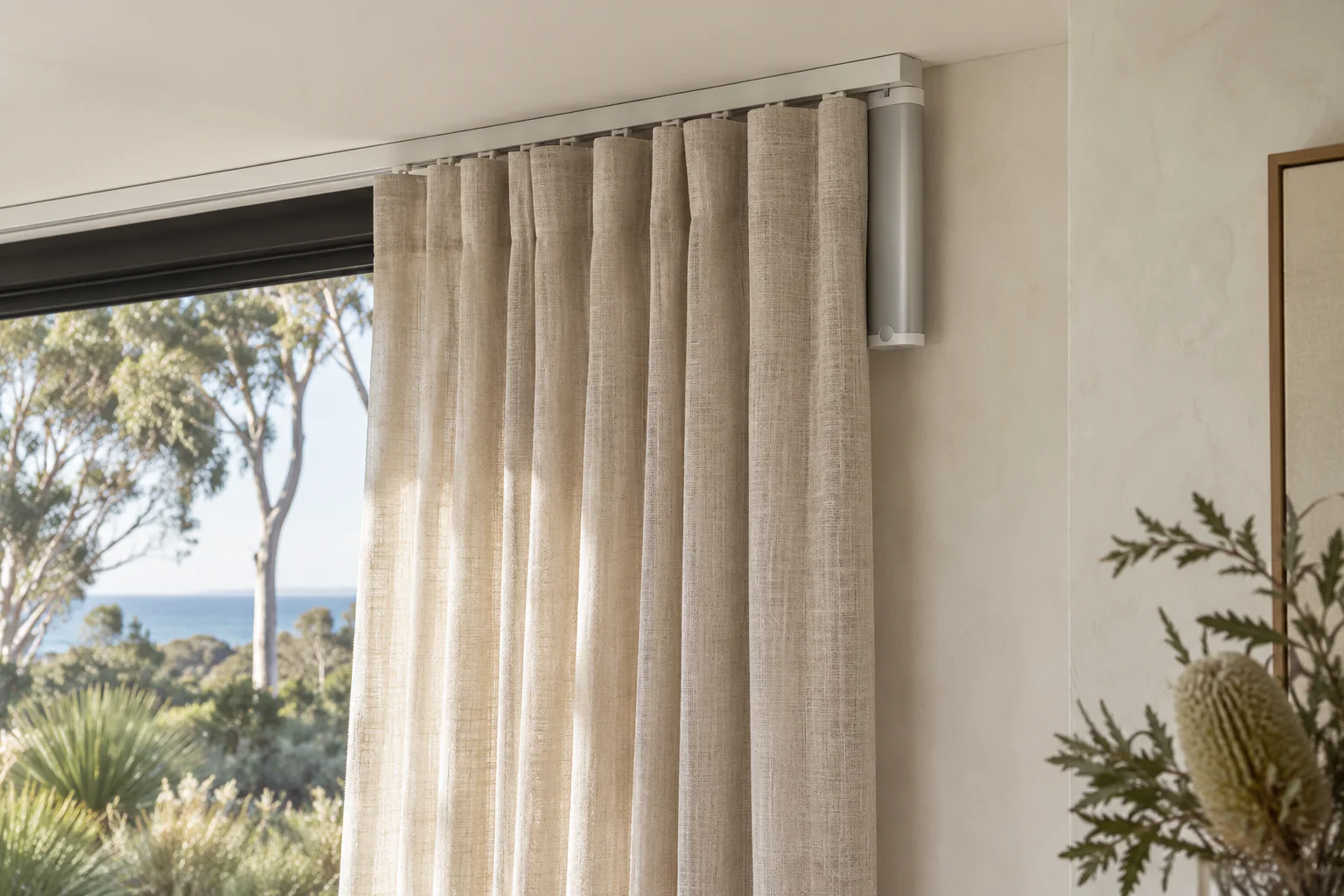 Illustrative slim curtain motor housing at the end of a ceiling-mounted rail beside the final curtain folds.