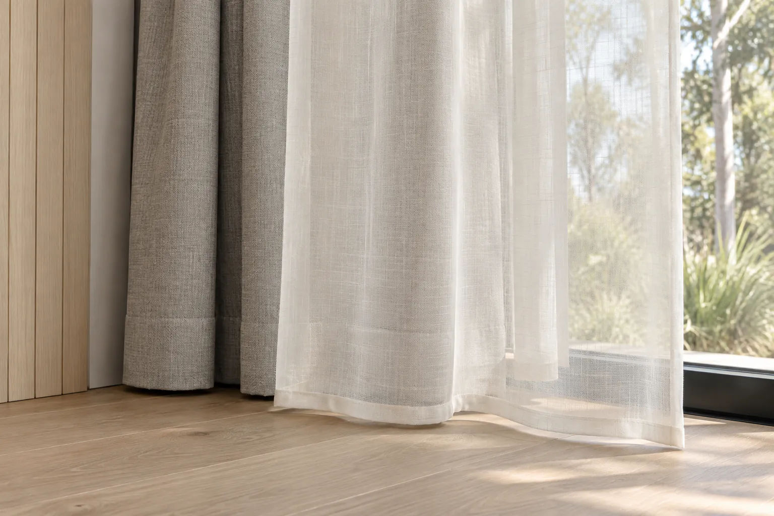 Ivory sheer curtain overlapping opaque stone fabric, with separate sewn hems above a pale timber floor.