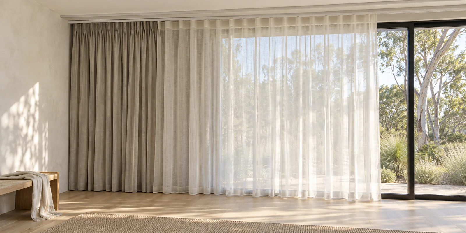 Ivory sheer curtains in front of stone blockout curtains on separate ceiling-mounted tracks, with an overlapping section showing both layers.
