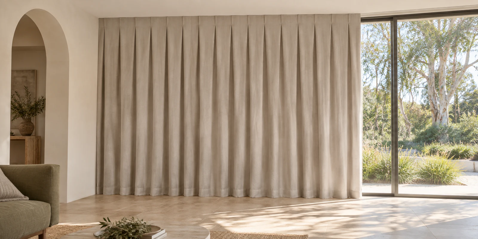 Floor-length oatmeal reverse-pleat curtains with a flat-faced heading above soft vertical folds.