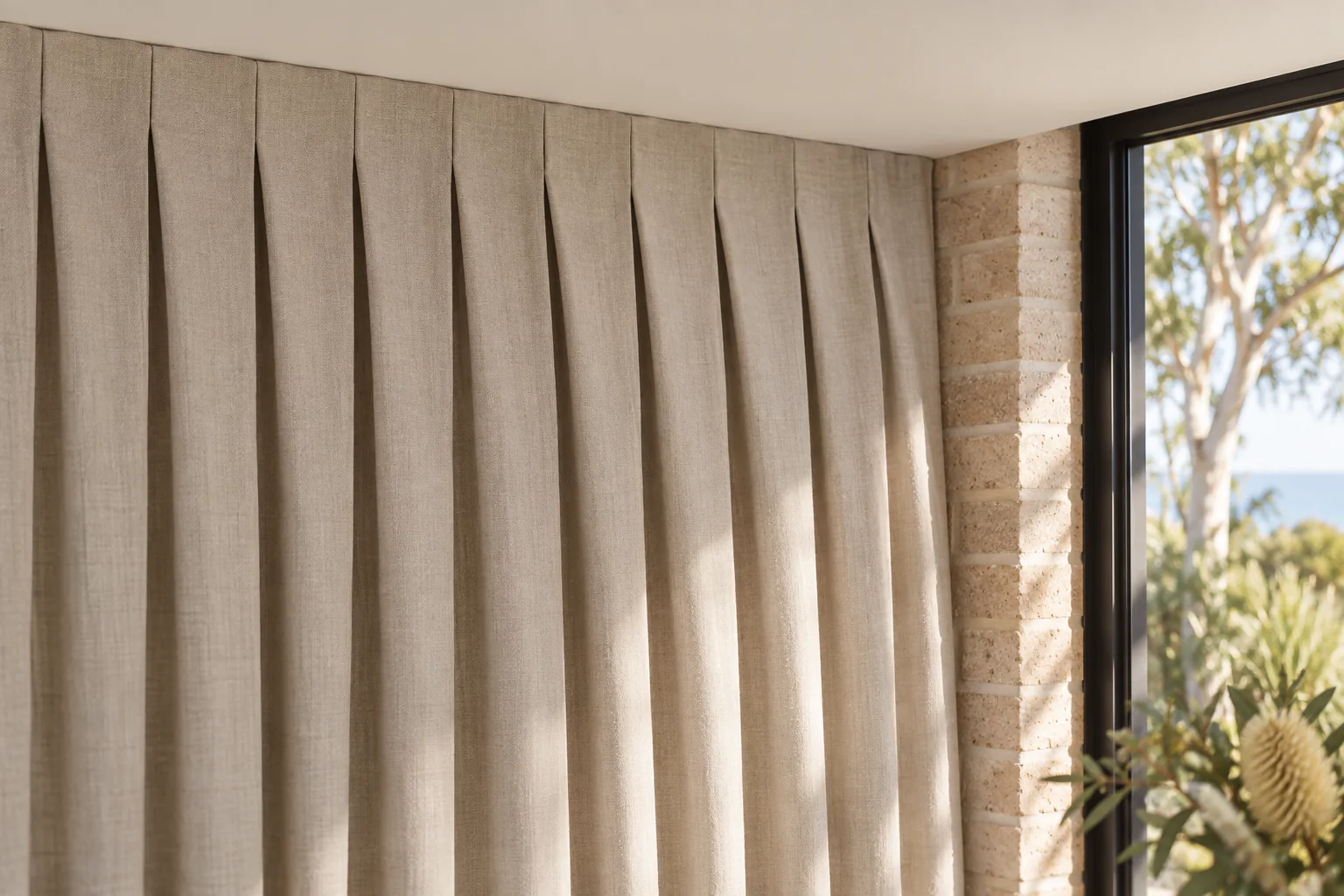 Flat-faced inverted pleats above relaxed vertical folds beside sandy brick and black-framed glazing.