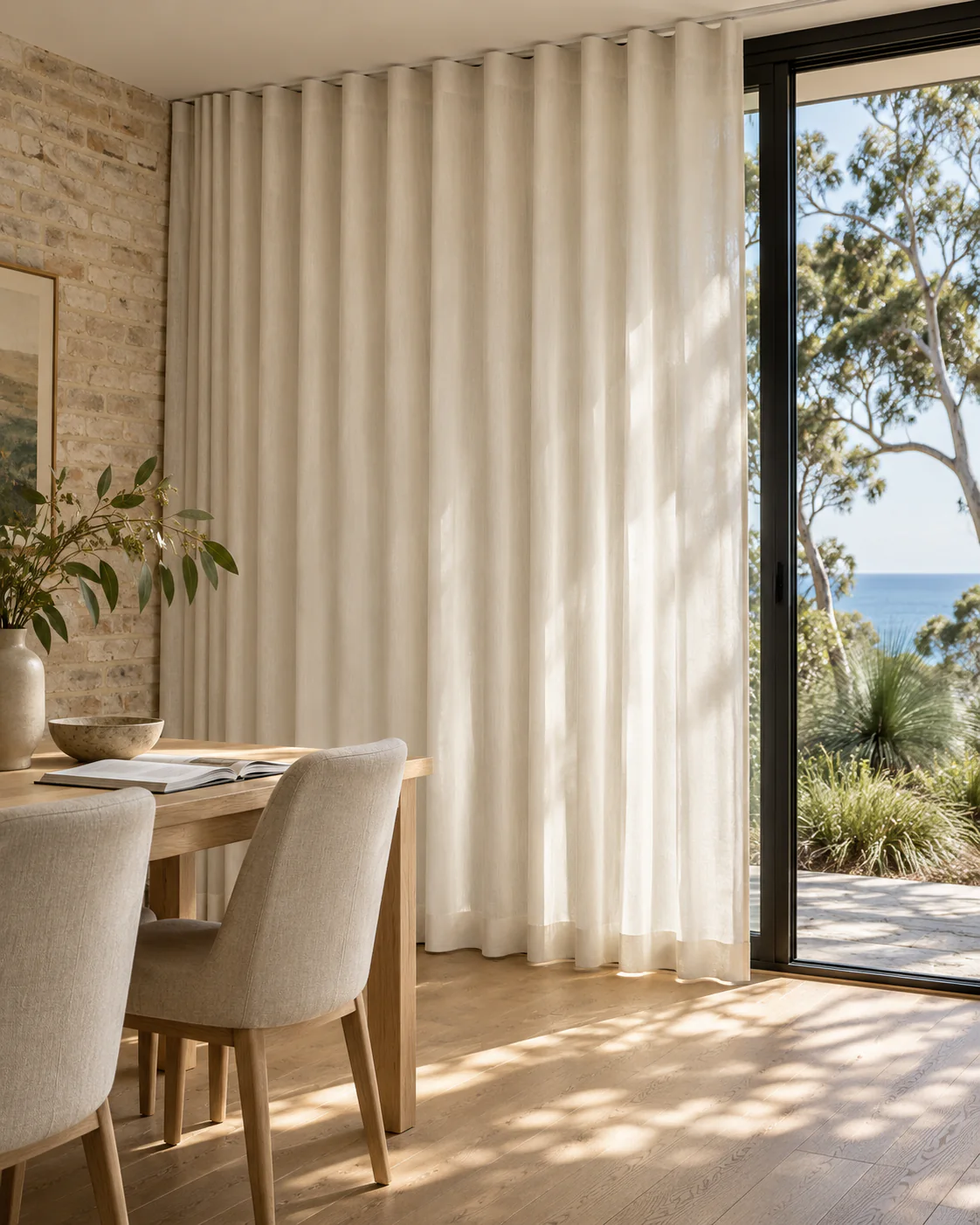 Full-height wave curtains framing black-steel glazing in a coastal brick interior.